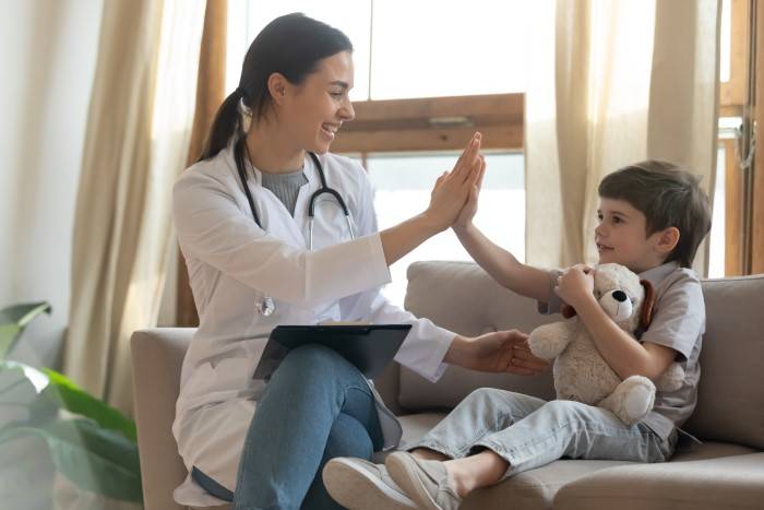 nurse gives child high-five while sitting on couch